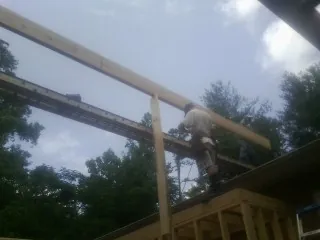 Carpenter setting a ridge beam over a new addition frame — Ice Dam Removal by Roofing Brothers in Otego