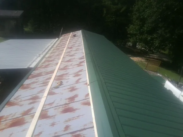 Old rusted panels beside newly installed green metal roofing — Wind Damage Roof Repair by Roofing Brothers in Otego