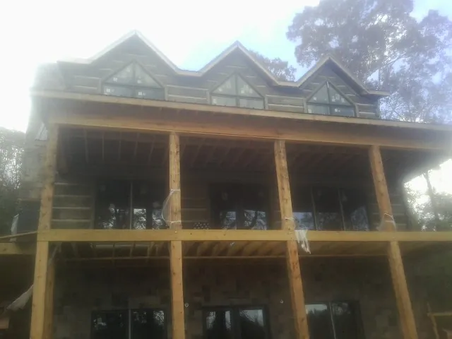 Dormers and porch framing on a large log home under construction — Roof Coating work by our crew in Otego