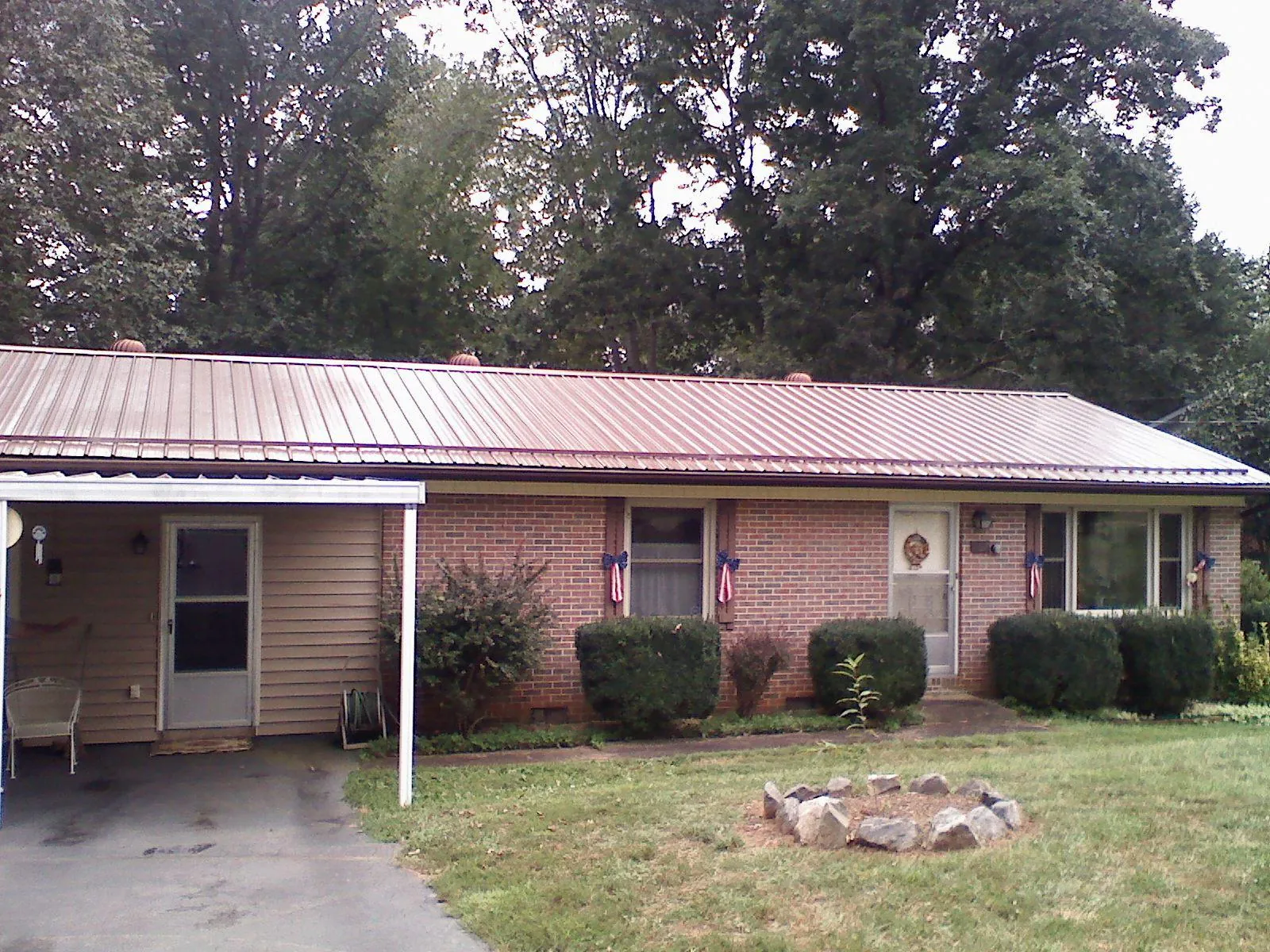 Bronze metal roof and carport on a brick ranch home — Roof Repair work by our crew in Otego
